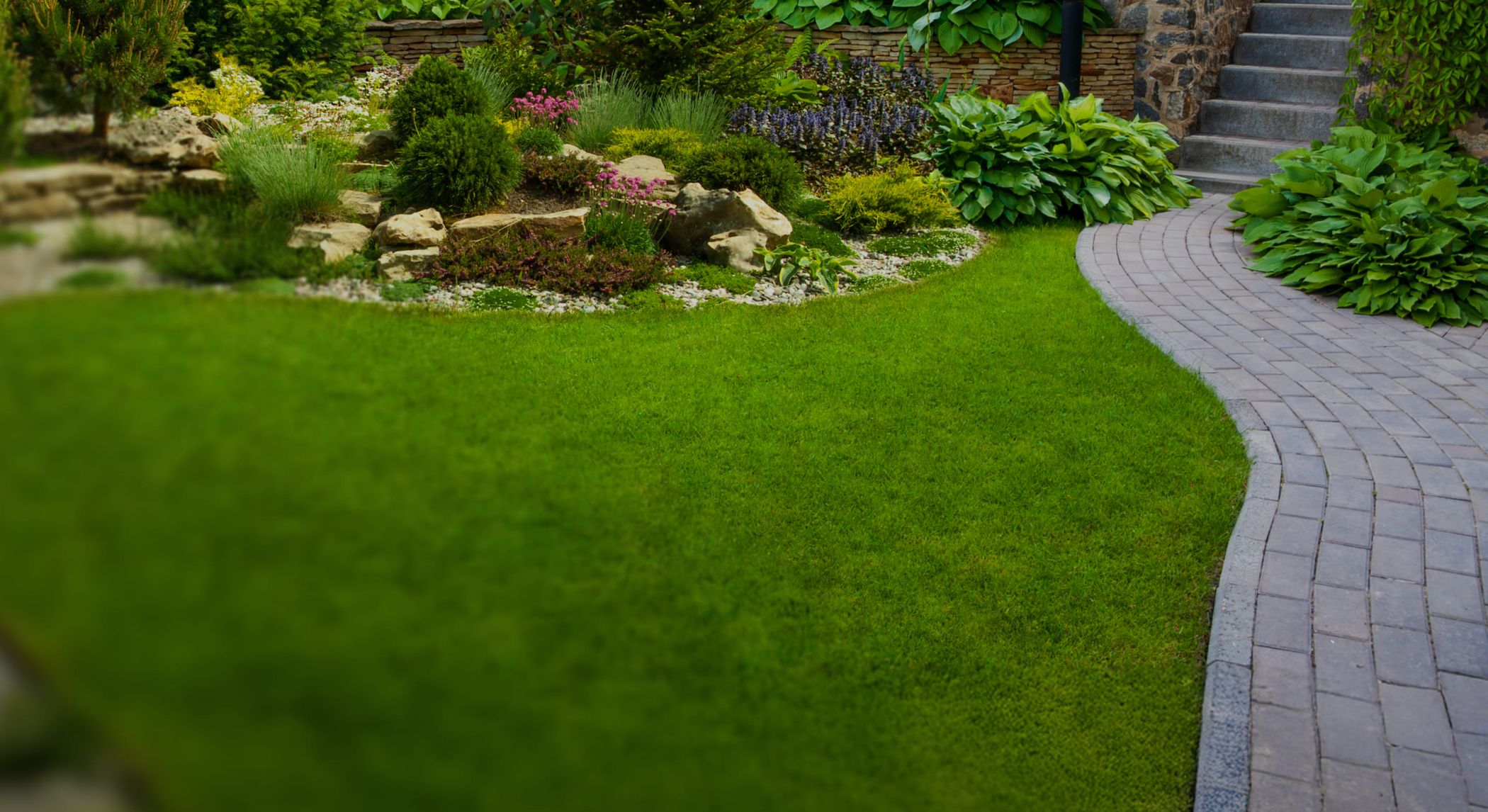 Gepflegter Garten mit Natursteinweg, Blumenbeeten und sattem Rasen